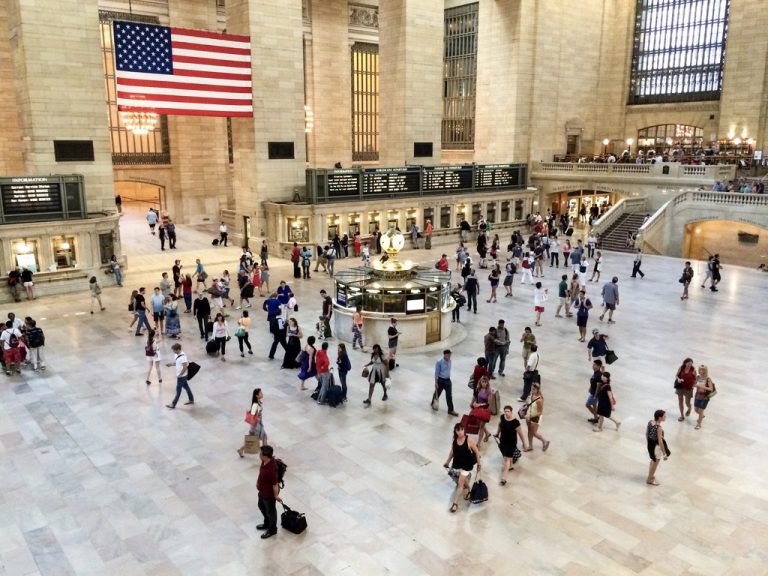 The Main Concourse from the West Balcony, with the post-9/11 American flag overhead and the brass information booth at center.