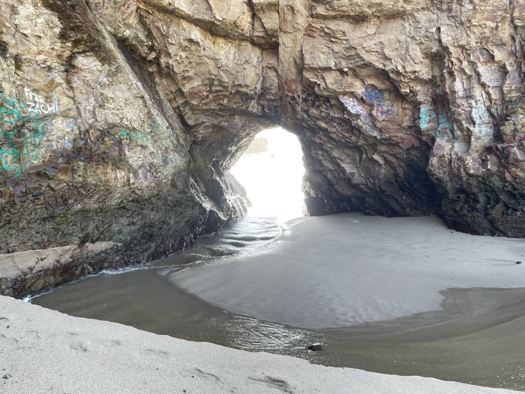 View through a sea cave opening onto the cove's sandy beach