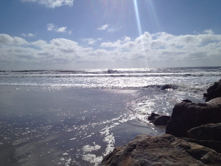 Morning sun rays scatter across the surf at Long Beach, Long Island.