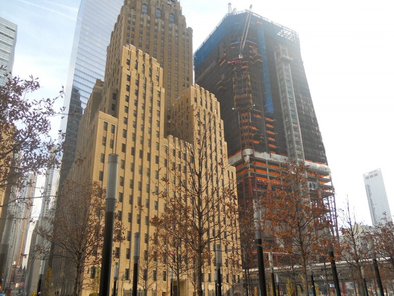 The classic architecture of Lower Manhattan's historic buildings frames One World Trade Center under construction, a vivid juxtaposition of old and new in the heart of the city.