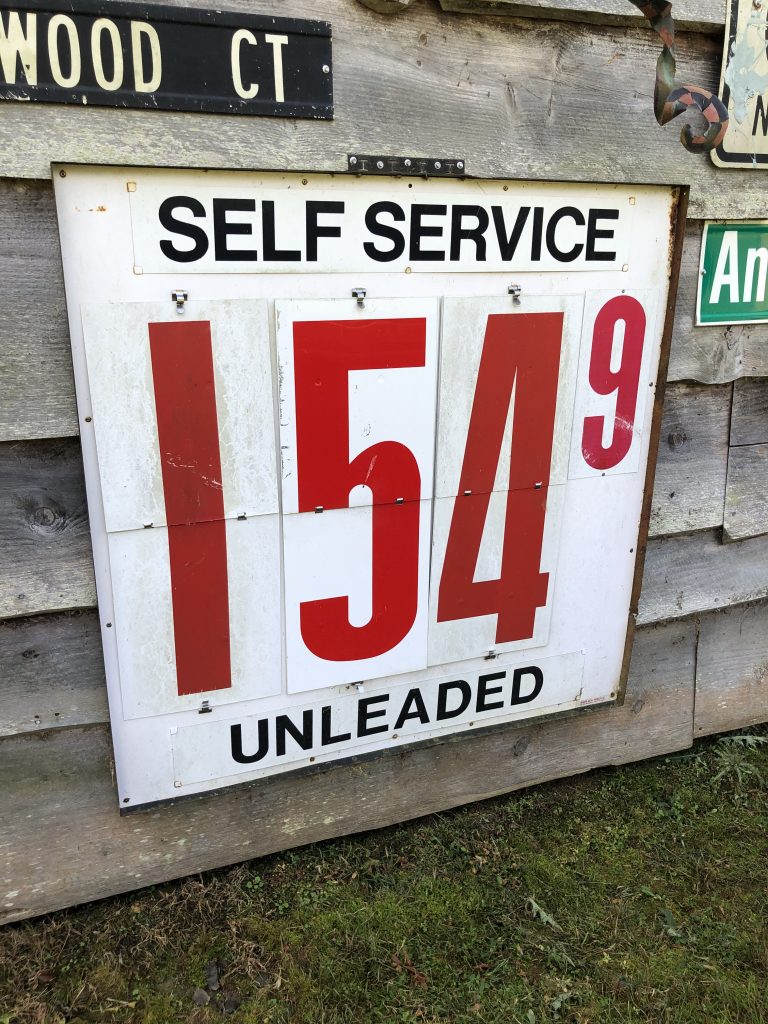 Self-service gas price sign: $1.54 per gallon unleaded, with Wood Ct street sign above