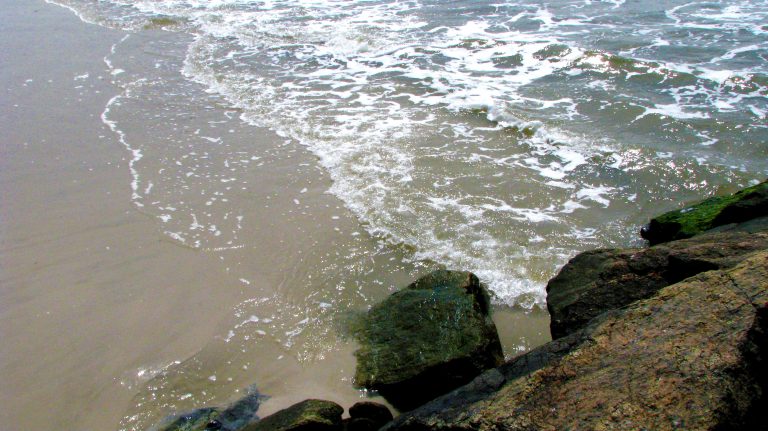 Foaming surf washes around the mossy jetty rocks.